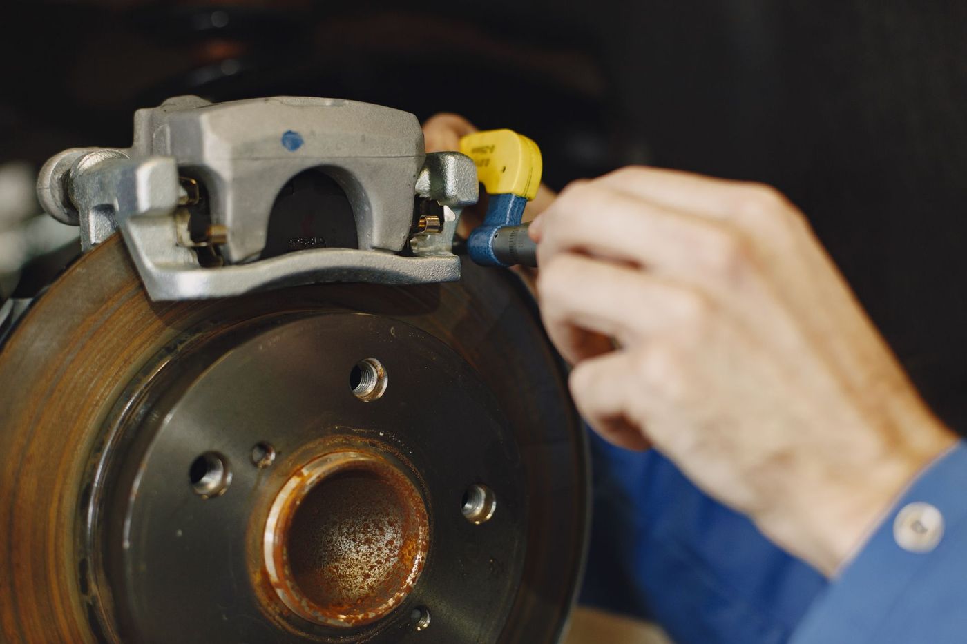 Gloved hand working at a disc brake and caliper with the wheel removed
