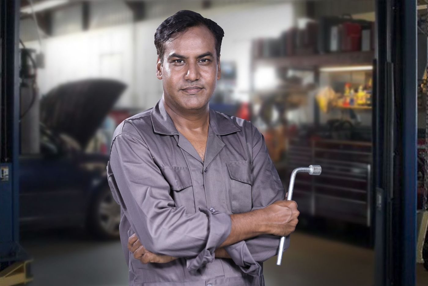 Technician in a plain work shirt holding a lug wrench