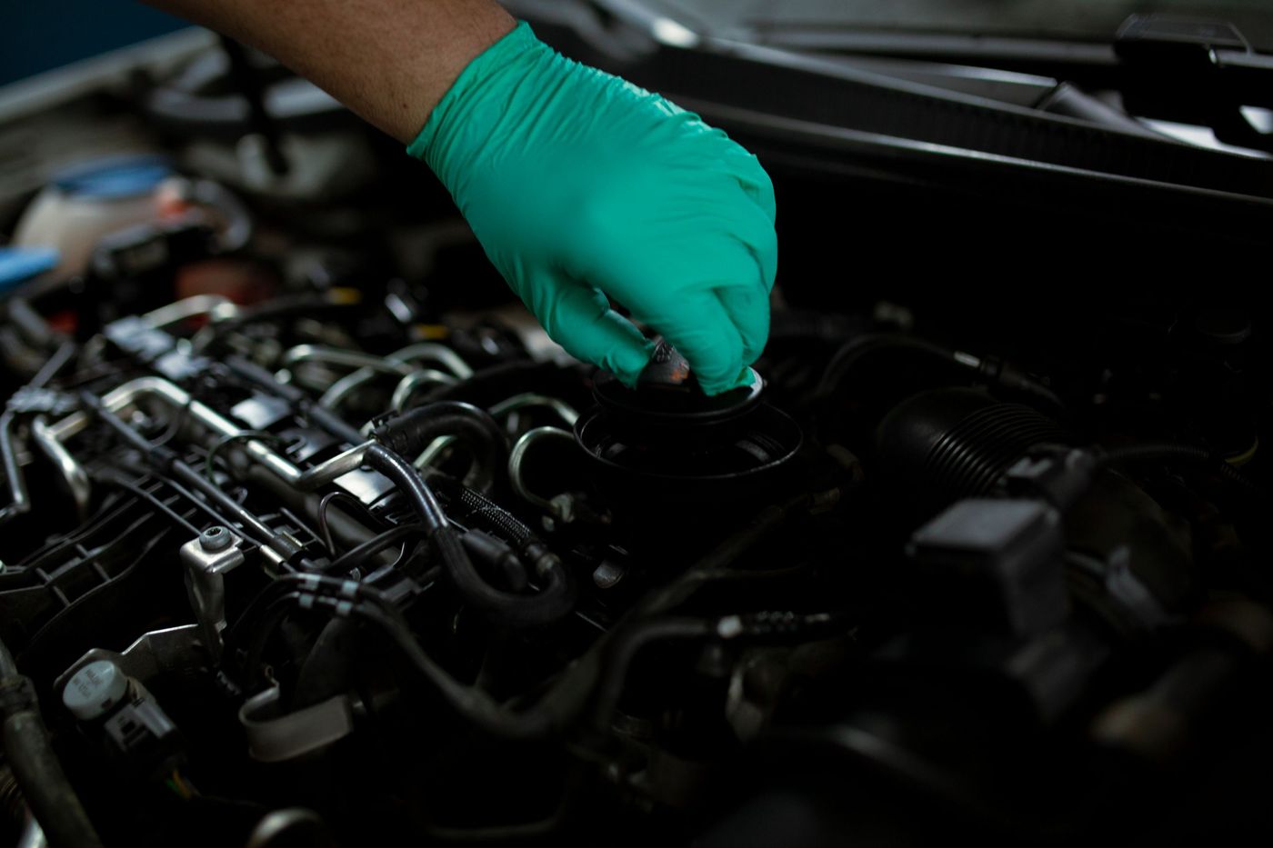Gloved hand opening the oil filler cap on a modern engine